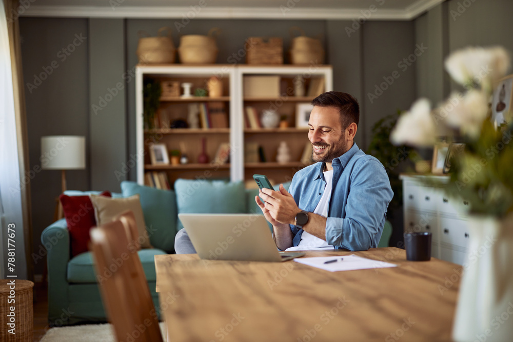A cheerful freelance man scrolling through social media while on his break in front of his laptop at home office. A cheerful freelance man scrolling through social media while on his break in front of his laptop at home office.