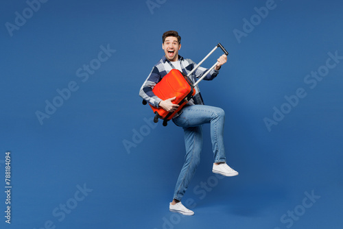 Traveler sideways man in shirt casual clothes hold suitcase bag pov lay guitar isolated on plain blue background Tourist travel abroad in free spare time rest getaway Air flight trip journey concept
