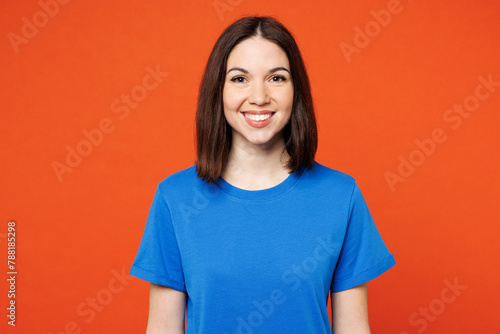 Young smiling happy cheerful satisfied woman she wear blue t-shirt casual clothes look camera with toothy smile isolated on plain red orange color wall background studio portrait. Lifestyle concept. © ViDi Studio