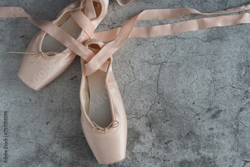 A pair of pink ballet slippers with a ribbon tied to the toe photo