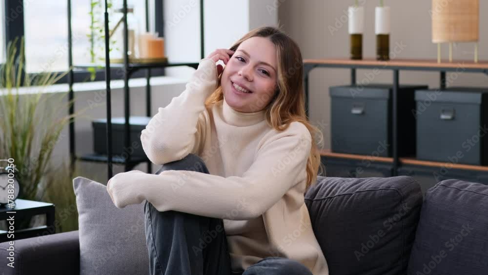 Portrait of a charming and smiling Caucasian woman laughing, looking at camera while relaxing and resting on sofa at home living room. Portrait of a charming and smiling Caucasian woman laughing, looking at camera while relaxing and resting on sofa at home living room.