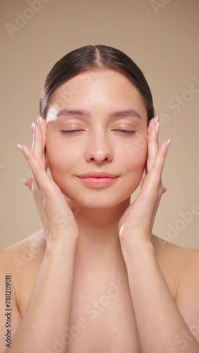 Beautiful Young Woman Touches Her Perfect Face. Natural Cosmetic Skincare Products. Woman demonstrate moisturizing facial care. Elevating Close-up. Slow motion, vertical video