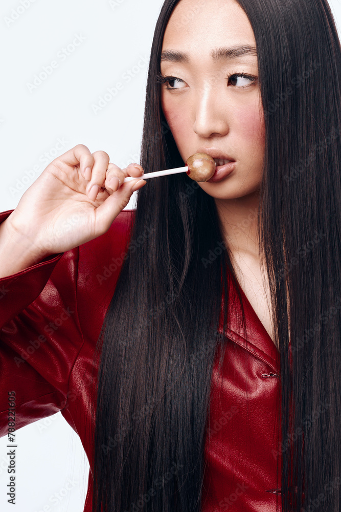 Young woman enjoying a lollipop with black hair and red jacket Young woman enjoying a lollipop with black hair and red jacket