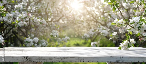 White blossoms and a white wooden table set against a spring backdrop of apple trees.