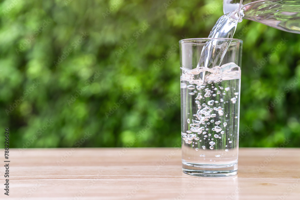 Pouring pure water from a bottle into a glass on the table in the morning light. Pouring pure water from a bottle into a glass on the table in the morning light.