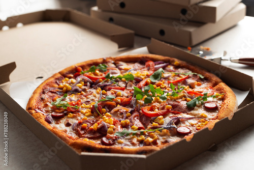 Large Pizza in open carton box and cutter on kitchen table closeup view