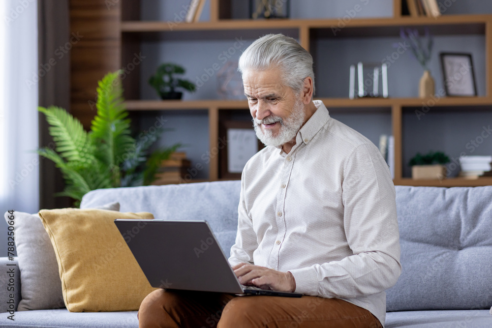 Senior man using laptop on cozy sofa at home Senior man using laptop on cozy sofa at home