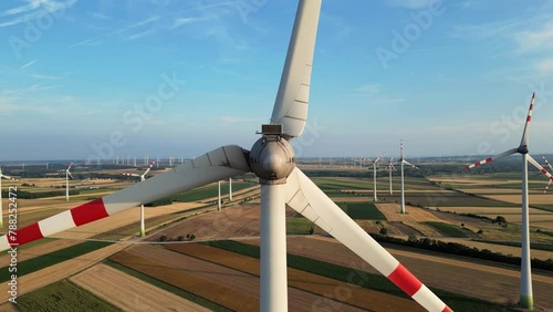 Large wind turbines with blades in field with sunset colors on the background. Summer countryside with wind turbines and agricultural fields. Alternative renewable energy, located Austria, Wien (ID: 788252472)