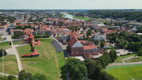 Aerial footage of Kaunas castle, situated in Kaunas old town, Lithuania. Beautiful church towers above the skyline of Kaunas old town. Nemunas and Neris rivers confluenceand forest in the background (ID: 788256204)