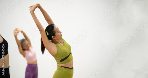 A woman is stretching her arms above her head while two other women look on photo