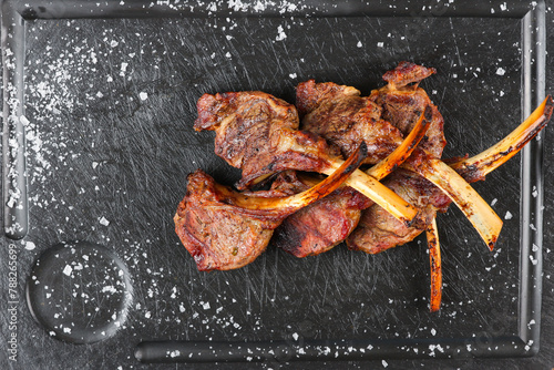 Lamb chops. Close up photo with some lamb chops grilled on barbecue and placed on a black plate with salt next to it. Lamp grill cooking.