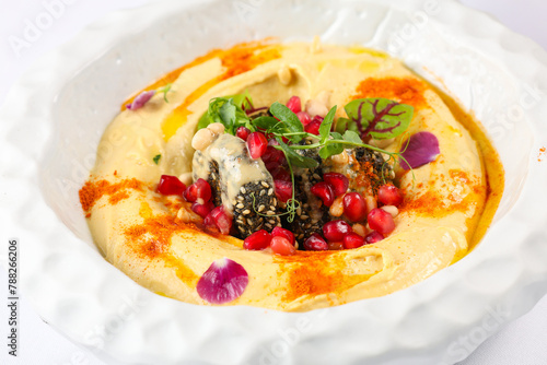Humus popular food in Middle Eastern cuisine. Close up photo with a gourmet dish made from humus oil seeds and pomegranate.