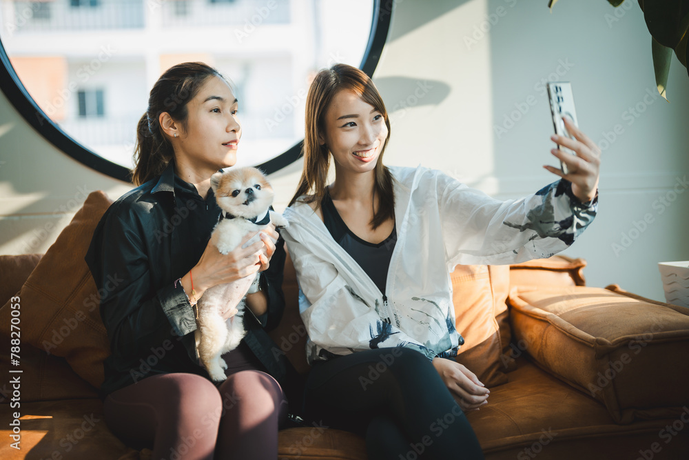 Two women are sitting on a couch with a dog in between them Two women are sitting on a couch with a dog in between them
