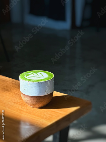 Cup of matcha latte green tea on wooden table.