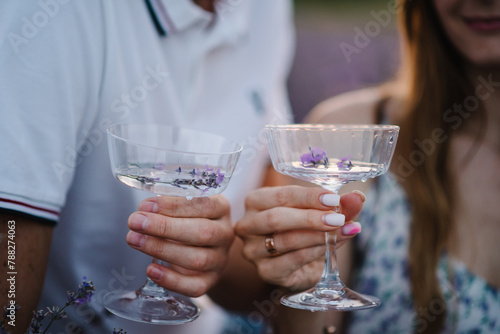 Photography Hands man and woman hold glasses of white wine with lavender sprigs and sit in lavender field