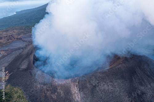 Smoke over volcano crater. Gray clouds ocean background. Vanuatu. Volcano accessible to tourists. © romankrykh