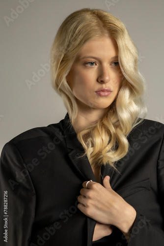 Beauty portrait of fashion young model with long blond hair on gray background