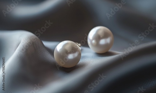 A set of pearl stud earrings arranged on a sleek satin material background
