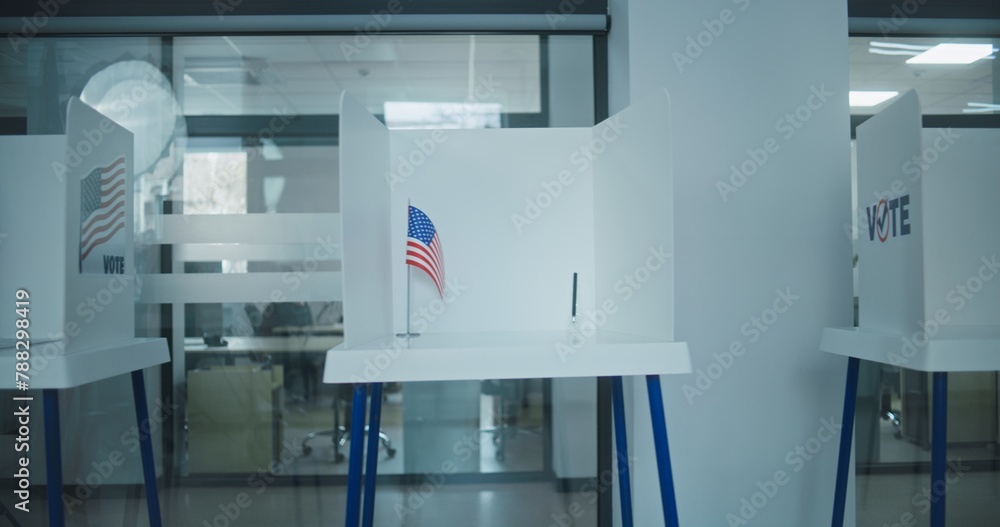 Dolly shot of voting booths with American flag logo in light polling station office. National Election Day in the United States of America. Political races of US presidential candidates. Democracy. Dolly shot of voting booths with American flag logo in light polling station office. National Election Day in the United States of America. Political races of US presidential candidates. Democracy.