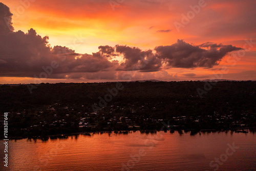 Scene of colorful sunset sky with clouds over evening city. Photo view from drone from the sea.