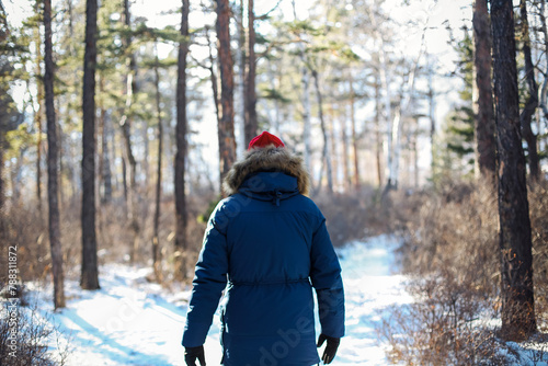 Traveller man in a blue winter jacket ad red cap in the woods. Sandy bay, Baikal lake, winter time photo