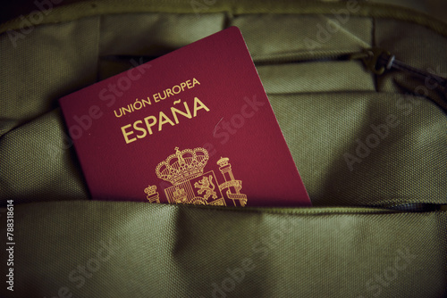A Spanish passport in a green backpack pocket