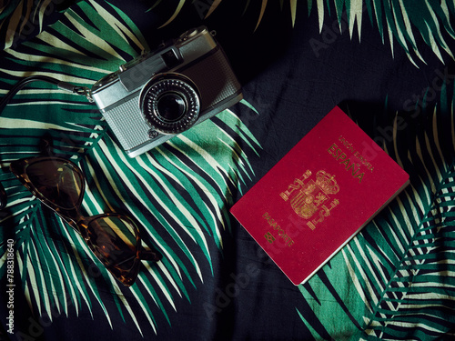 Foto A Spanish passport, a camera and sunglasses over a Hawaiian bedcover