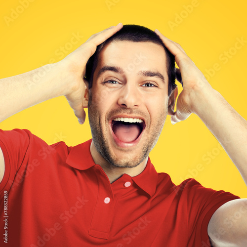 Unbeliveable! Very happy impressed shocked man, isolated against yellow background. Emotions and success concept. Excited male model with raise hands, wear red cloth at studio. Square. image photo