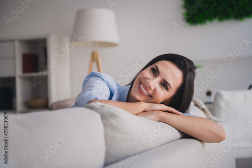 Photo of good mood pretty lady dressed blue shirt having rest couch smiling indoors house room