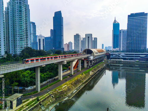 A red and white Jabodebek LRT train travels on a track. © Neilstha Firman