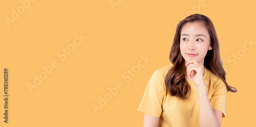 Surprised happy beauty asian woman looking copy space in excitement. Expressive facial expressions. Presenting some product. Beautiful girl look at blank space Isolated on yellow background	
