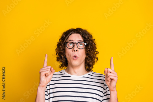 Close up photo of young amazed funny nerd guy direct fingers above head much useful information isolated on yellow color background