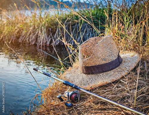 Fishing Rod and Worn Straw Hat of  Riverbanks with Reeds