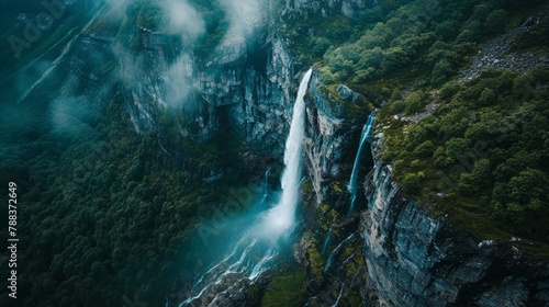 Aerial view of a majestic waterfall thundering down into a pristine mountain