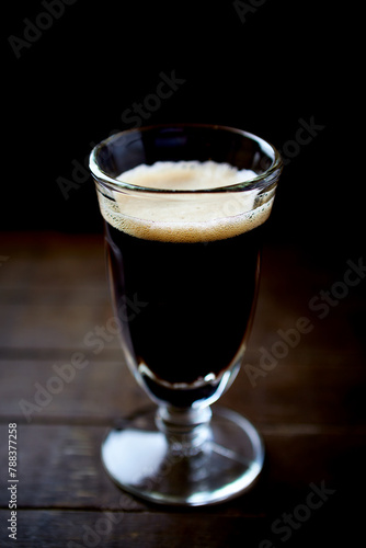 Glass of dark beer on dark wooden background. close up.