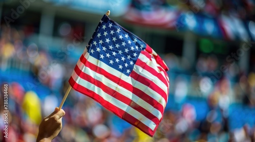 A patriotic gesture of a hand waving the American flag during a sporting event or rally, symbolizing unity and pride. 