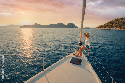 Luxury travel on the yacht. Young woman on boat deck sailing the sea. Yachting on sunset. © luengo_ua