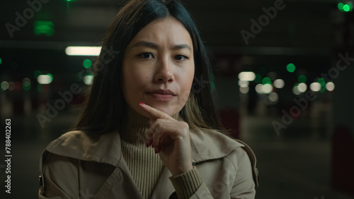 Close up thoughtful doubtful Asian woman ethnic chinese japanese girl puzzled thinking korean lady in car parking lot think idea uncertain doubt distrust suspect difficult decision question consider photo