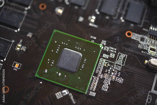 A brown printed circuit board with a processor chip and video memory strips. Electronic components on the graphics card.