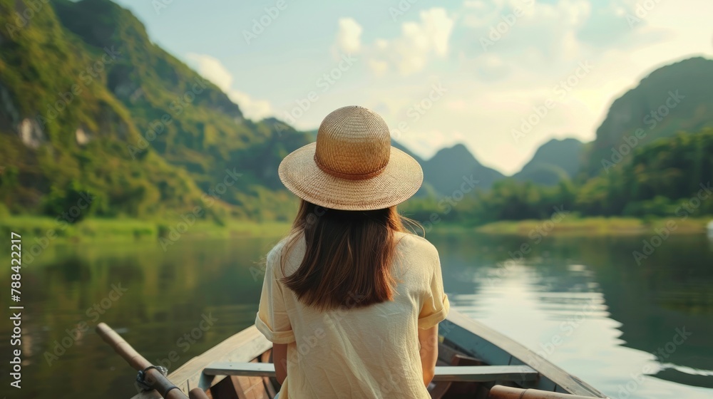 Young woman views Mountain View while sitting on a rowboat in Ninh Binh, Vietnam.