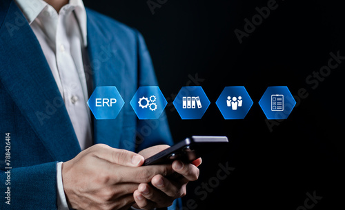 ERP, Enterprise resource planning concept. Businessman use smartphone to analyzing ERP system on virtual screen. Connections between business intelligence, HR and CRM modules.