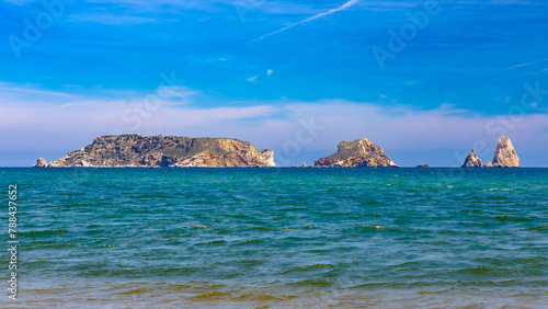 Las Islas Medas emergen del Mediterráneo frente a Estartit, Cataluña, destacando su silueta rocosa contra un cielo azul en primavera. photo