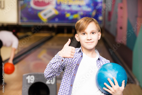 Cute kid boy teenager with ball at bowling club