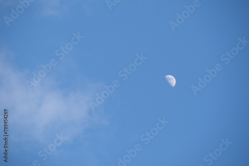 A view of the moon with a blue sky with some clouds. le Croisic, France - April 16, 2024.