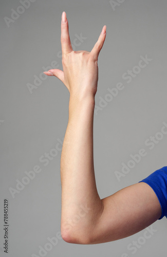 Female hand sign against gray background in studio