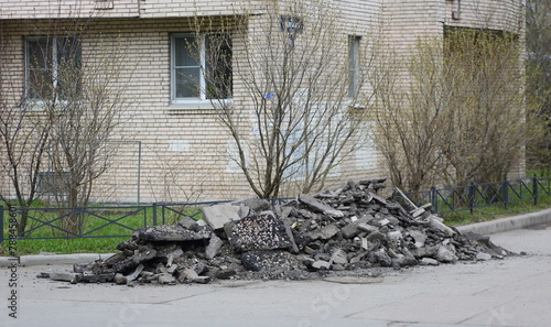 A pile of broken asphalt lies near the wall of an apartment building