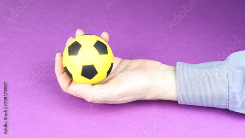 Man's hand holds a balloon, with purple background.