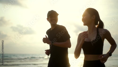 Young couple wearing sportswear running on sand sea ocean beach outdoor. Couple young two friends running or jogging at seaside for healthy lifestyle. Training athlete work out outdoor concept. photo