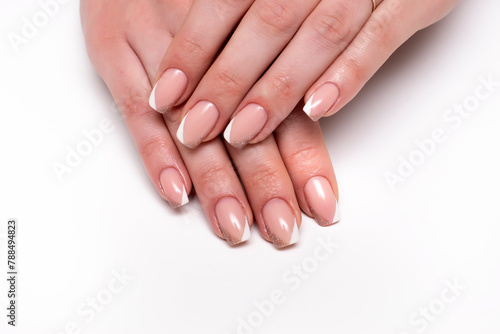 White beige shiny French manicure on short square nails close-up on a white background