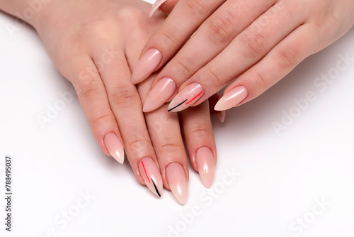 Beige manicure on sharp long nails with black-orange stripes close-up on a white background. Nude manicure.